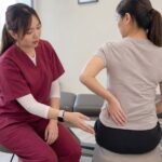 Ivy from One Spine explaining sitting posture and tailbone pain in a clinic setting